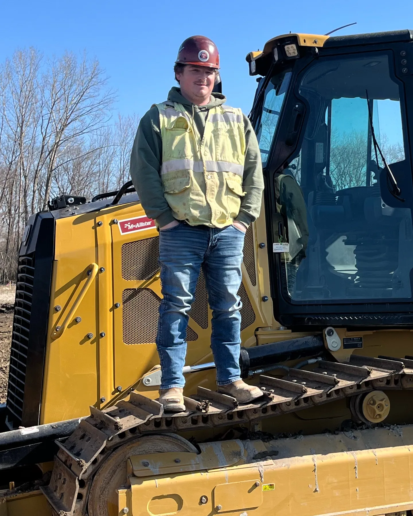 Portrait of Matt Brooks, owner of GridView UAS Services, wearing a hard hat and hi-vis vest on a CAT dozer at a jobsite